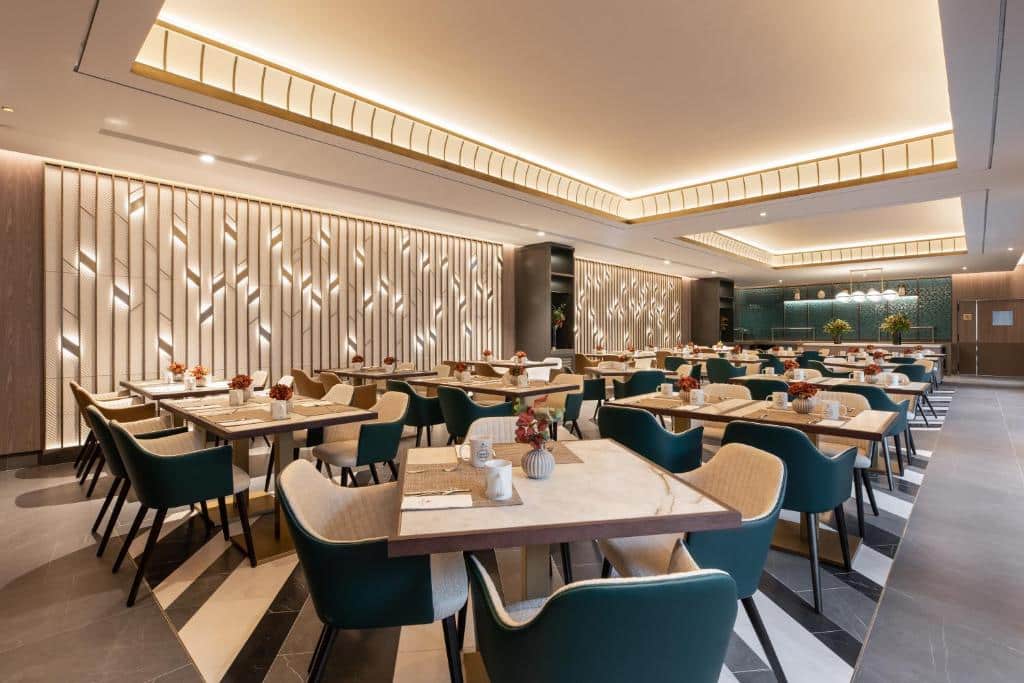 Zona de refeições do restaurante do Eurostars Ambassador, com mesas e cadeiras bem dispostas, iluminação contemporânea e painéis decorativos nas paredes.