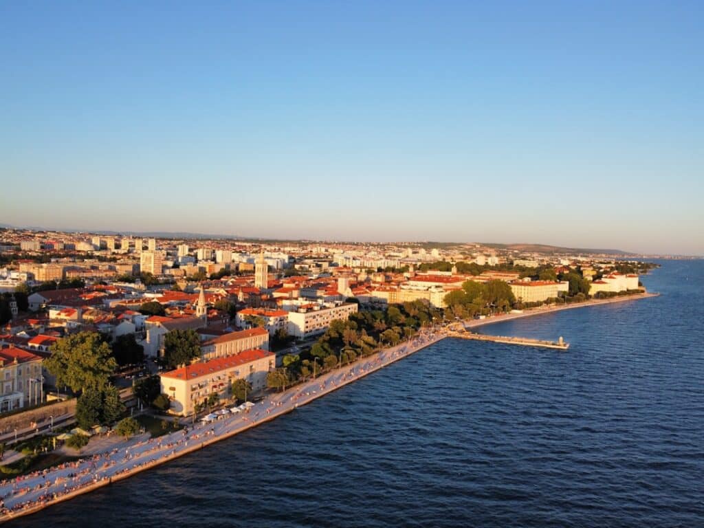 Vista aérea de cidade litoral com praia, mar azul e edifícios residenciais e comerciais, a Cidade Velha de Zadar, na Croácia