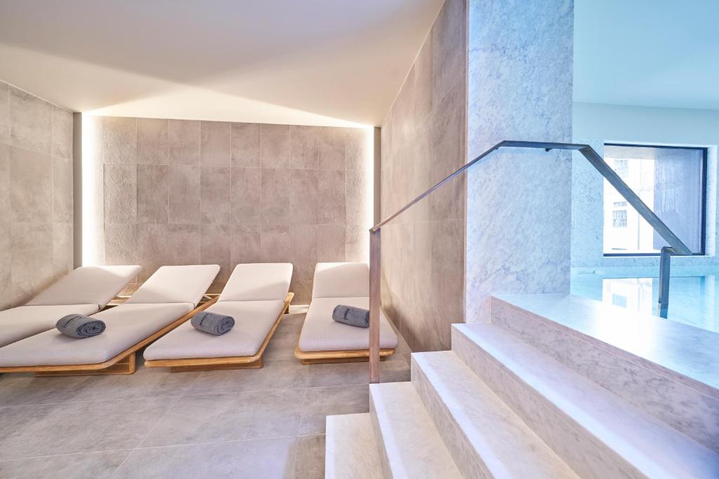 Espreguiçadeiras com toalhas enroladas alinhadas junto à piscina do PortoBay Flores, num ambiente de spa moderno.