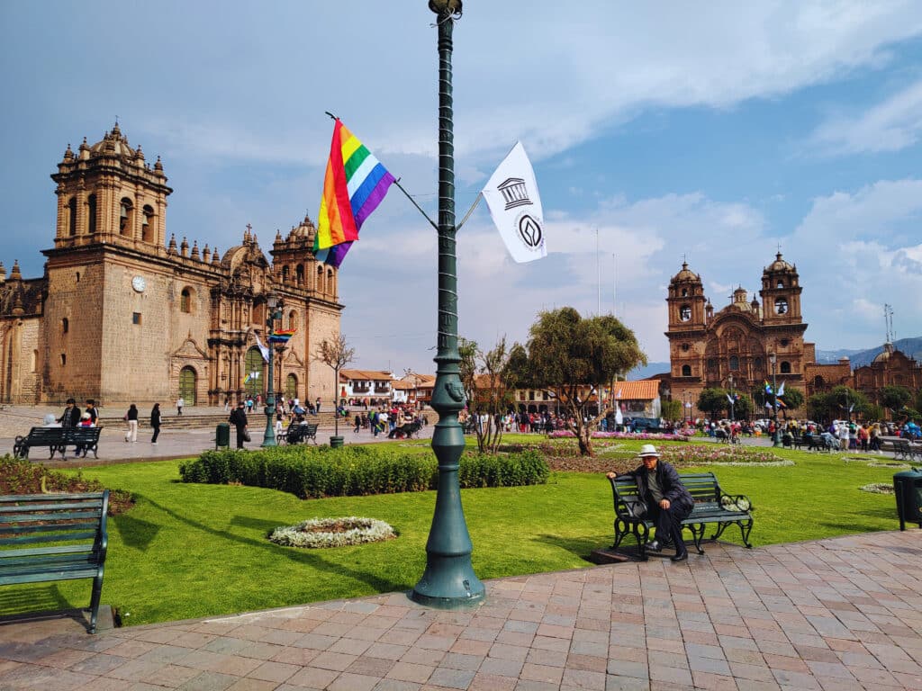 Praça de Armas de Cusco com um candeeiro ao centro, a catedral à esquerda e a Igreja da Companhia de Jesus à direita