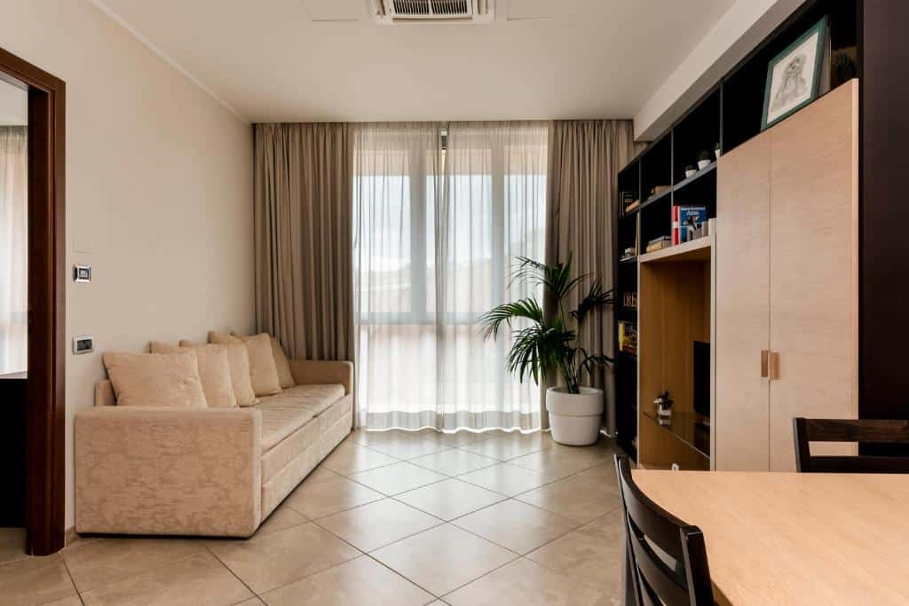 Sala de estar moderna com sofá bege, cortinas claras e mesa de jantar de madeira clara