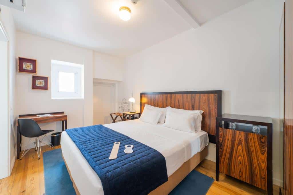 Quarto do Lisboa Prata Boutique Hotel com uma cama de casal, um móvel à direita com comodidades para café, à esquerda uma mesinha com candeeiro e uma secretária com cadeira