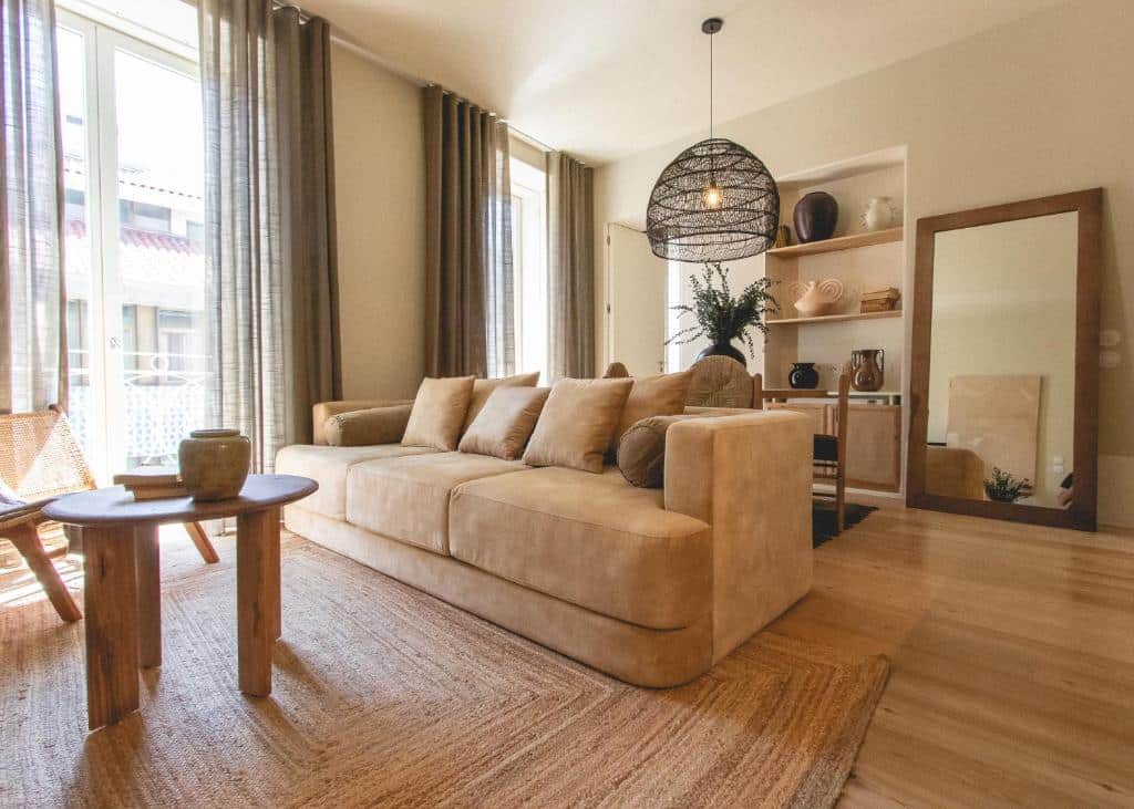 Sala de estar do Village Aparthotel By BOA, com sofá à direita e uma pequena mesa redonda de madeira em frente.