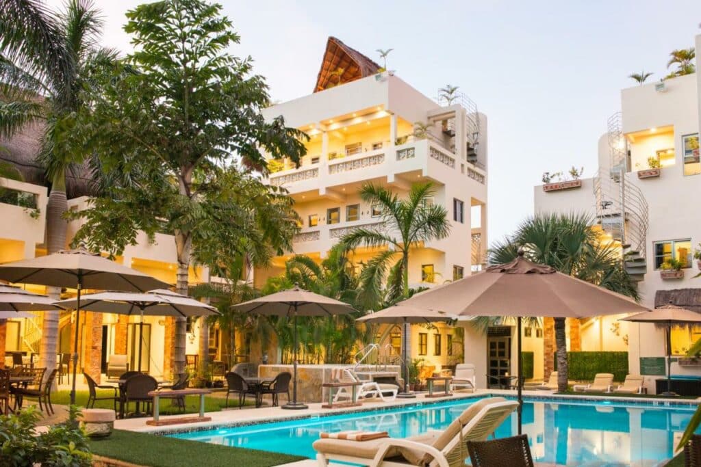 Piscina do Álamos Inn Hotel con Jacuzzi y Piscina com a construção em redor iluminada e árvores à volta