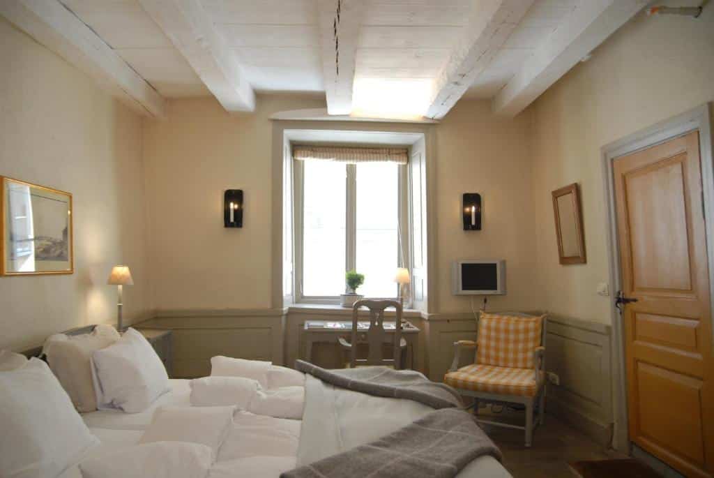 Quarto do Hotel Sven Vintappare com cama de casal, cómoda com candeeiro e mesa com cadeira.