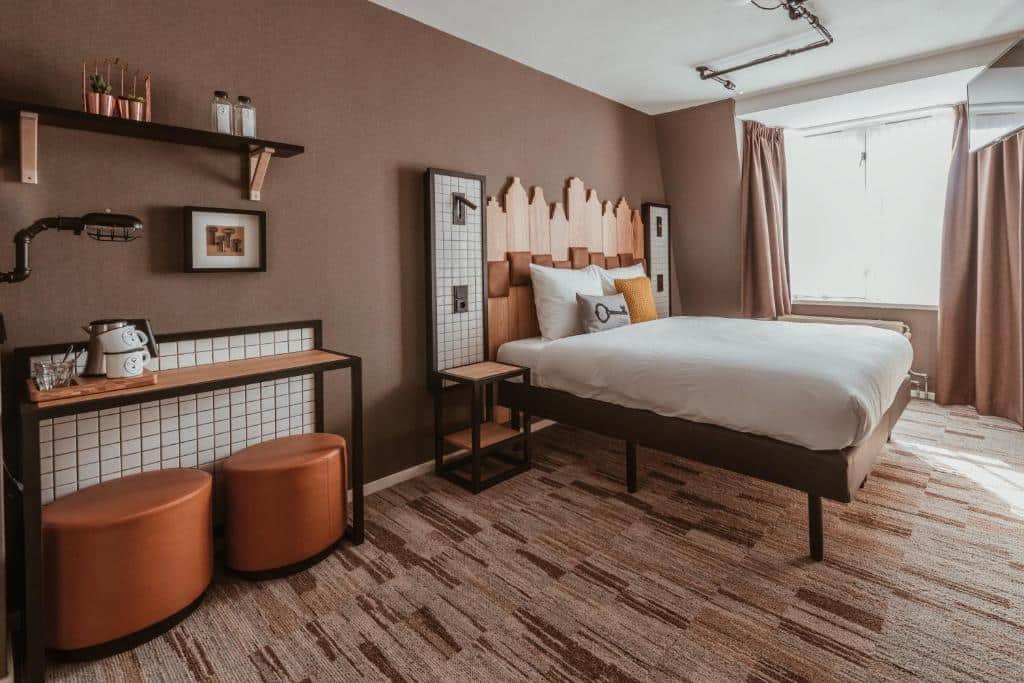 Quarto do Mr. Jordaan, com cama de casal e um balcão com dois puffs e zona de café, e uma janela do lado direito a iluminar o quarto
