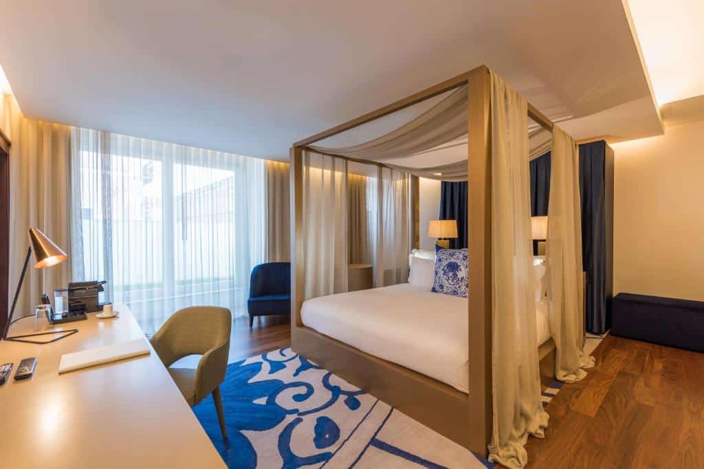 Suíte espaçosa do NAU Palacio do Governador com cama de casal, janela ampla com cortinas e secretária, em Lisboa