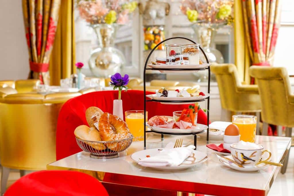 Mesa posta para o pequeno-almoço no Boutiquehotel Das Tyrol, com doces, frios, queijo, sumo de laranja, um ovo e sobremesas, numa elegante sala de refeições.