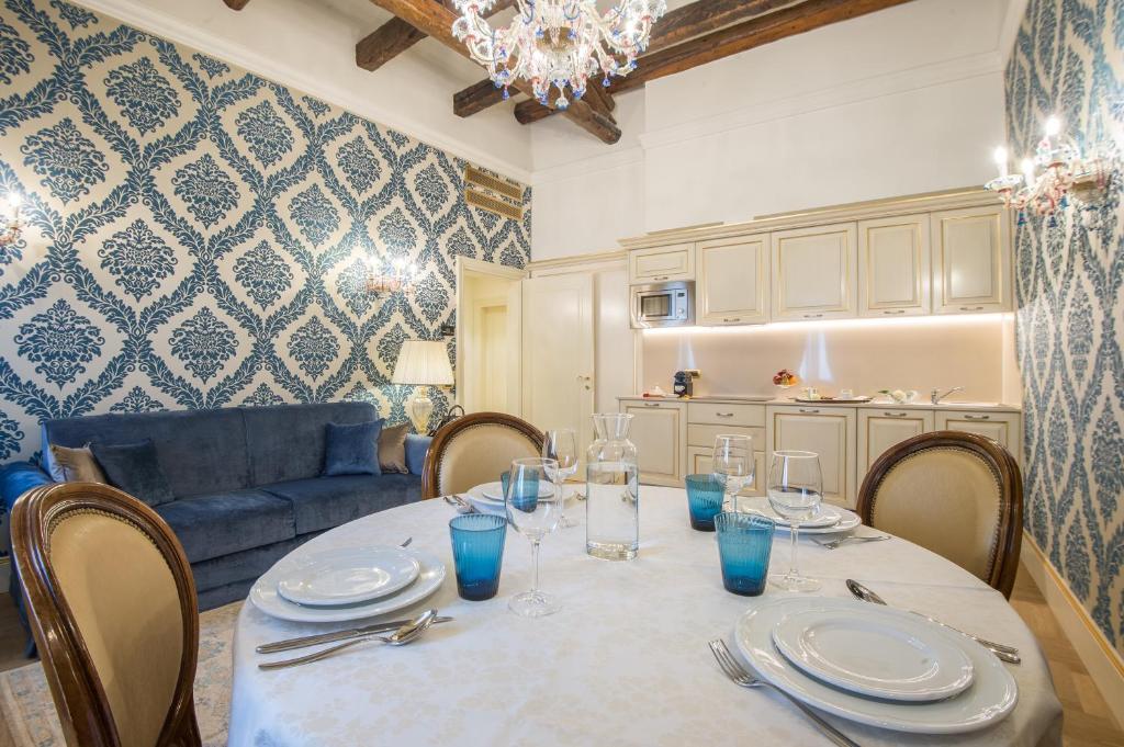 Sala de estar e de jantar em estilo rústico com decoração em tons de azul e móveis escuros, com sofá de veludo azul, mesa de jantar com cadeiras estofadas e cozinha embutida