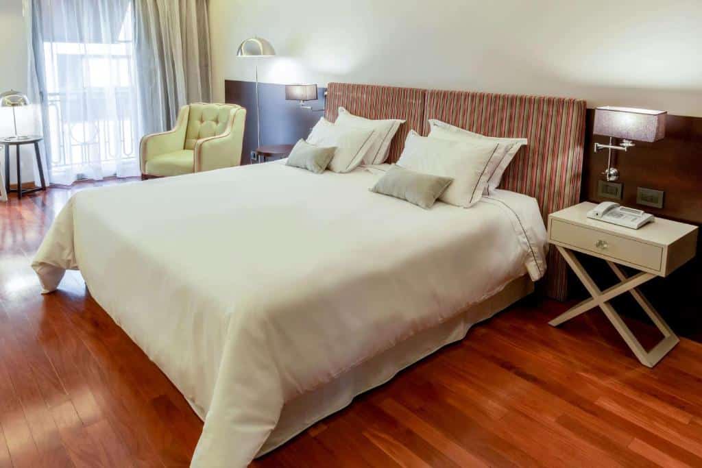 quarto do Esplendor by Wyndham Buenos Aires Tango com cama de casal, mesa de cabeceira e candeeiros, poltrona junto a uma janela com cortinas em tons claros