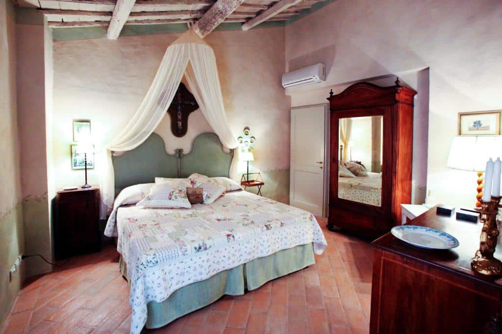 Quarto de casal com cama de dossel, roupeiro de madeira e pavimento cerâmico rústico