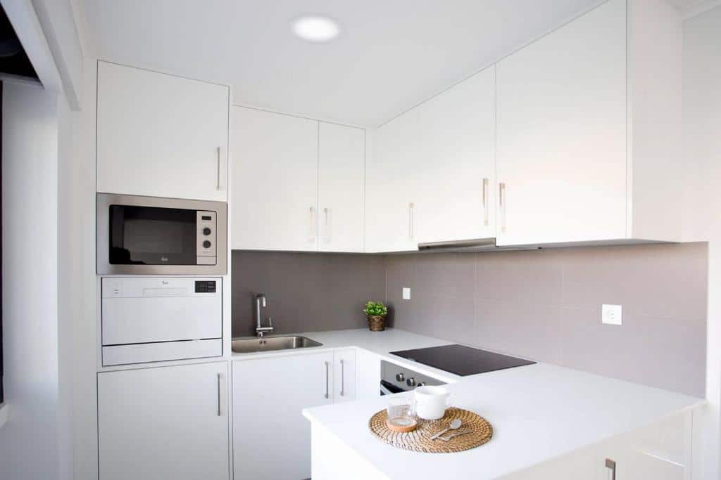 Cozinha branca do 137 LuxResidence com móveis, um micro-ondas, um forno elétrico, placa e uma bancada em L