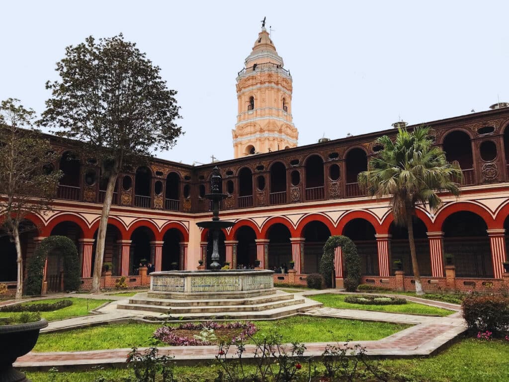 Fonte no jardim interior da Basílica e Convento de Santo Domingo, em Lima, com arcos vermelhos em redor