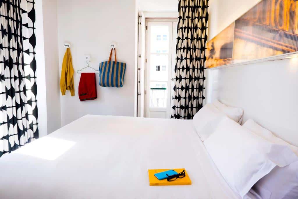 Quarto do Hotel Gat Rossio com uma cama de casal, uma pequena varanda e um quadro na parede por trás da cama.