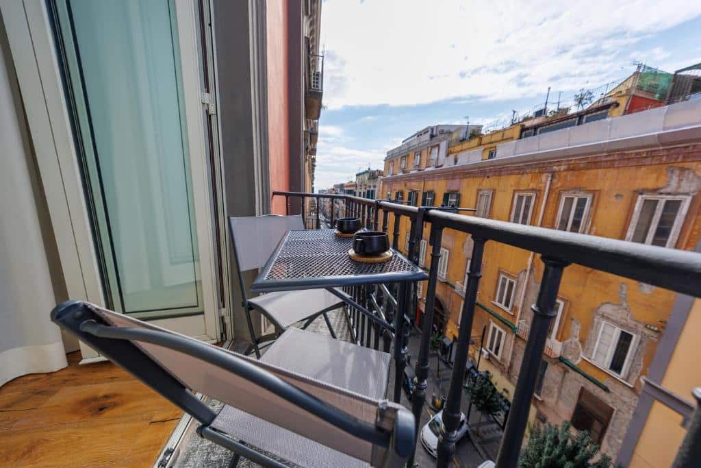 Varanda com mobiliário moderno no Centro Histórico de Nápoles, com gradeamento preto e vista para edifícios amarelos e construções antigas, no The Other Duomo House.