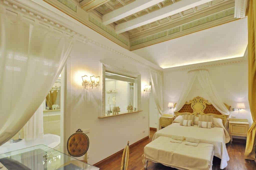 quarto do The Right Place 4U Roma Savelli Boutique Apartment, um alojamento local em Roma, com decoração clássica, cama de casal, janela trabalhada em vidro, mesa e candeeiro de cada lado, cadeiras acolchoadas e várias luzes nas paredes