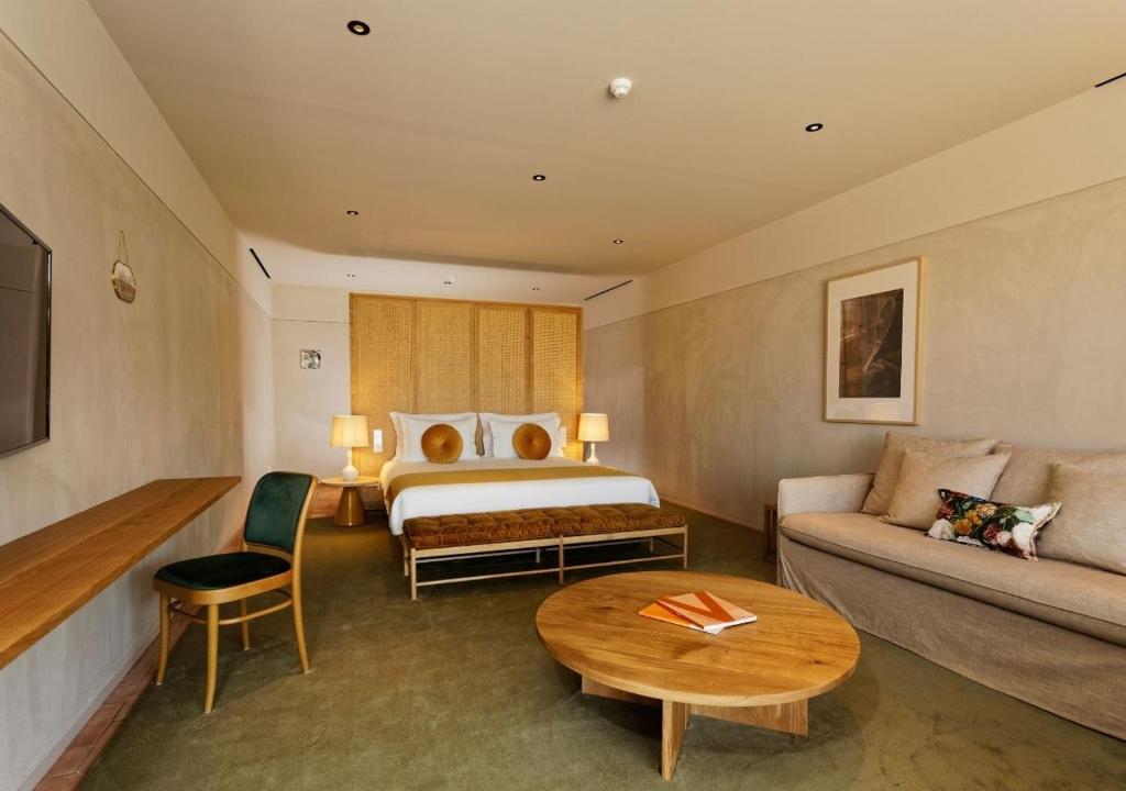 Quarto do Montebelo Vista Alegre Ílhavo Hotel com sofá, mesa e cama ao fundo.