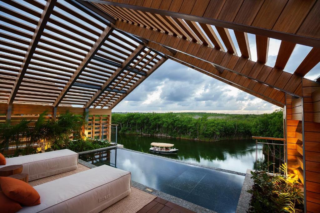 Piscina de bordo infinito no Banyan Tree Mayakoba com vista para rio e vegetação tropical.