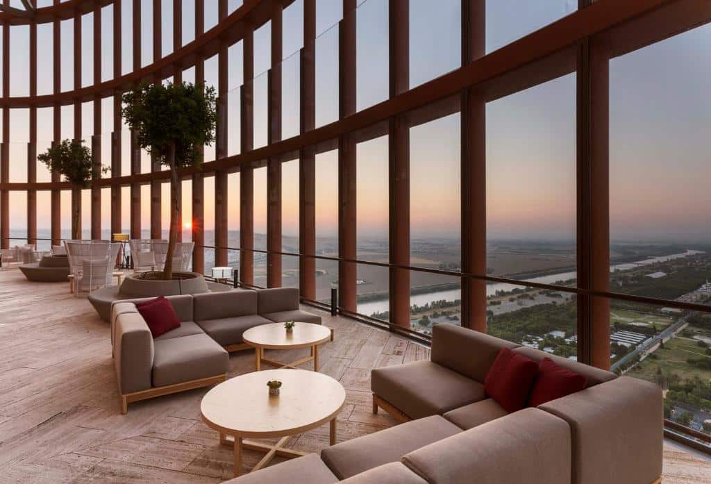 Restaurante do Eurostars Torre Sevilla com mesas e sofás e vista panorâmica sobre a cidade.