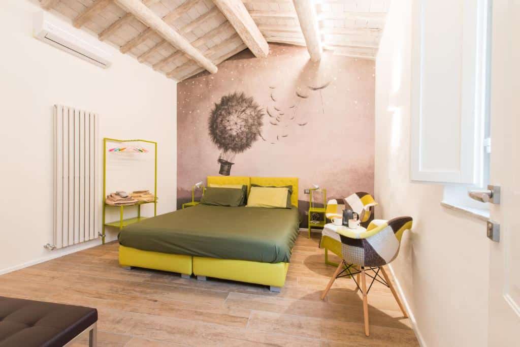 Suíte júnior da Fonte Gaia Experience, com 25 m², cama de casal verde-lima que se pode transformar em duas camas de solteiro, duas poltronas e uma pintura a preto e branco de um chapéu a voar, com flores a espalhar-se pelo céu