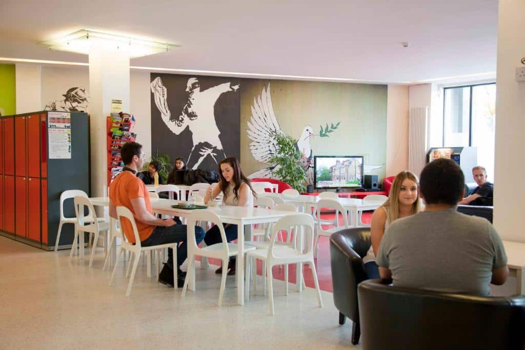 Pessoas reunidas num espaço de convívio no Abigail's Hostel, com desenhos e decoração colorida nas paredes.