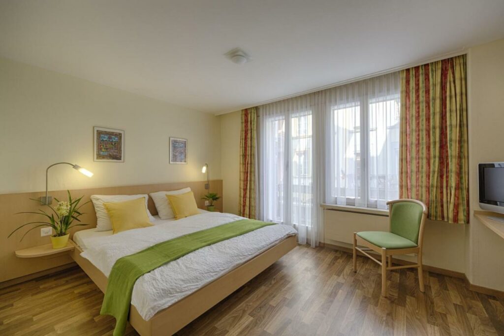 Quarto do Hotel Blume Interlaken com cama de casal e televisão sobre uma cómoda.