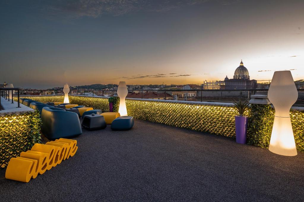 terraço do Hotel Relais Dei Papi, num ambiente aberto, com plantas e velas grandes, cadeirões e mesas de estilo moderno e vista para o Vaticano