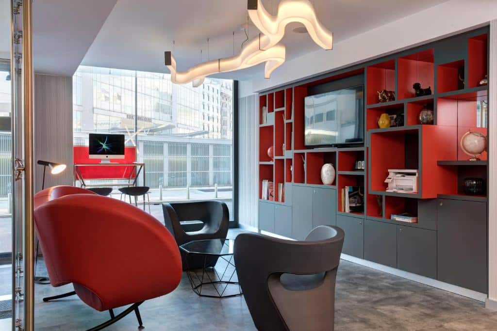 Sala de estar com poltronas vermelhas e candeeiro de forma sinuosa em tons de preto e vermelho no iQ Hotel Milano