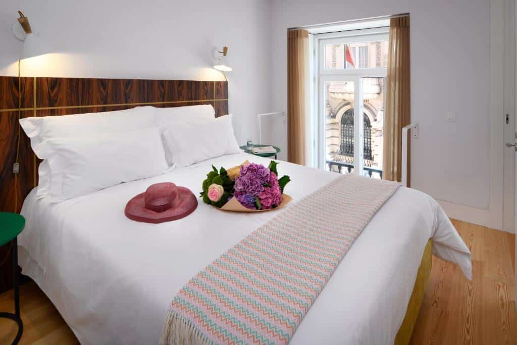 Quarto de uma das unidades do Ouro Grand by Level Residences com uma cama de casal espaçosa, uma janela com cortinas, candeeiros e pavimento de madeira