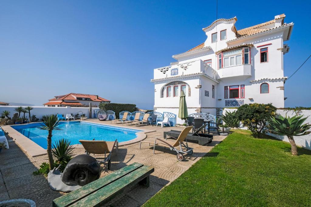 Propriedade do Casal Santa Virginia, uma casa grande branca com janelas vermelhas, jardim e piscina