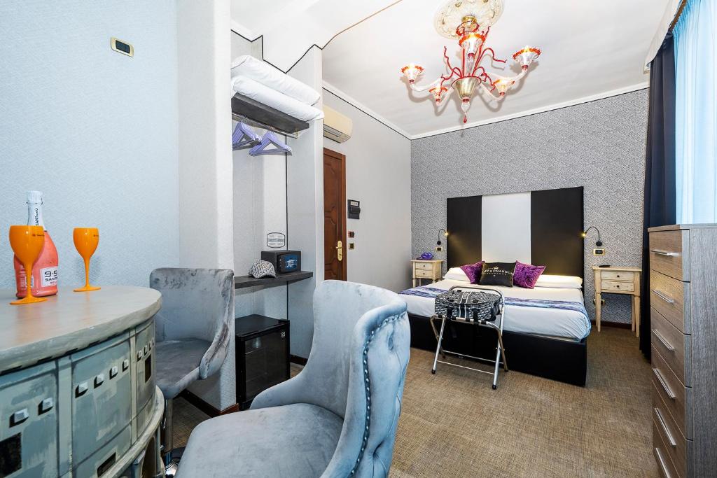 quarto do Hotel Relais Dei Papi, um dos hotéis baratos em Roma, com cama de casal, lustre requintado, dois cadeirões grandes em tons de azul-claro, um balcão trabalhado com taças em frente, cabides disponíveis e mesas com candeeiro de ambos os lados da cama