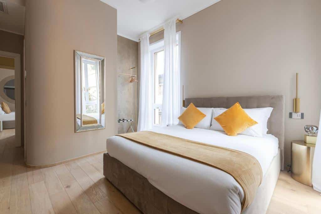 Quarto do Heart Milan Apartments San Sepolcro Duomo com uma cama de casal com almofadas, uma janela com cortinas, um espelho de corpo inteiro e um cabide de pé