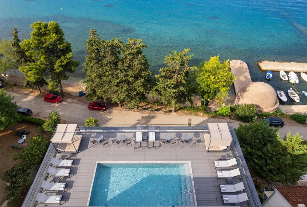 Piscina retangular azul com espreguiçadeiras brancas numa área de lazer à beira-mar, na La Vista Suites, em Kolovare