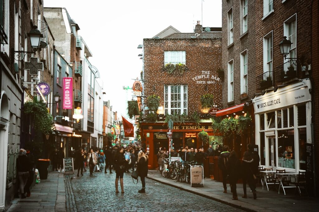 Rua movimentada com bares, restaurantes e lojas de estilo europeu, com iluminação acolhedora ao fim do dia em Dublin, na Irlanda.