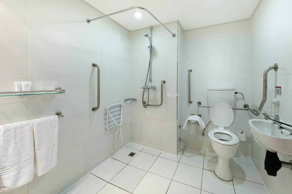Casa de banho acessível no Holiday Inn Express Cape Town City Centre com barras de apoio, chuveiro de acesso fácil, assento e sanita adaptada.