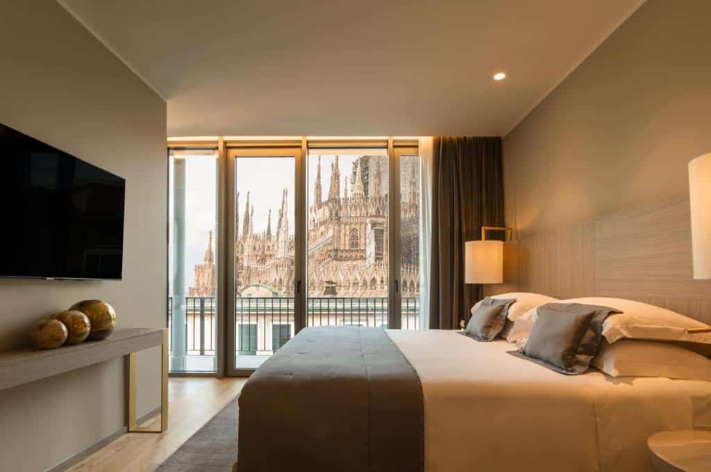 Quarto do Rosa Grand Milano com varanda ampla com vista para a Catedral de Milão, cama de casal, cabeceira com duas luminárias e televisão
