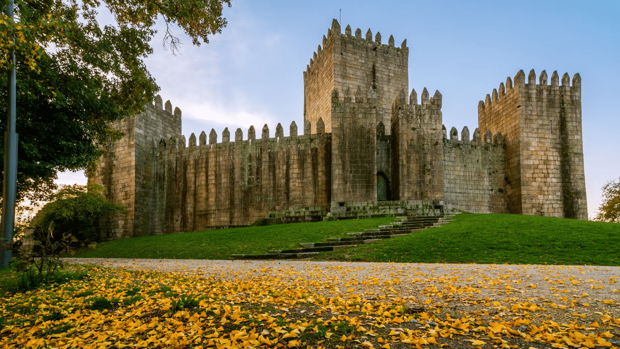 Castelo ao fundo durante o dia, com um jardim em frente.