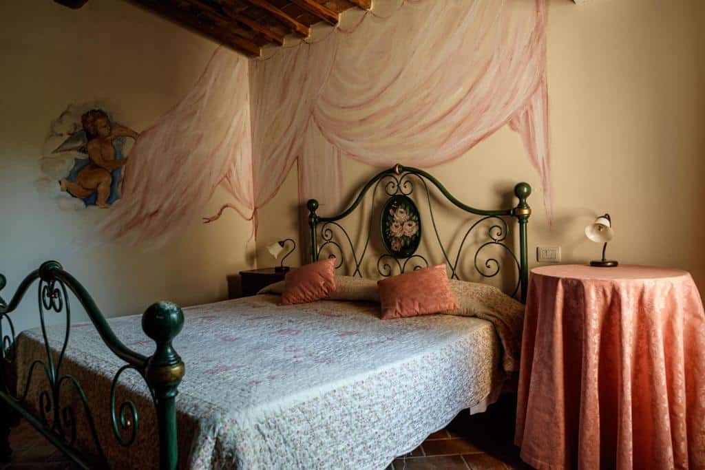 Quarto de casal com cama de ferro verde, cabeceira florida e decoração romântica