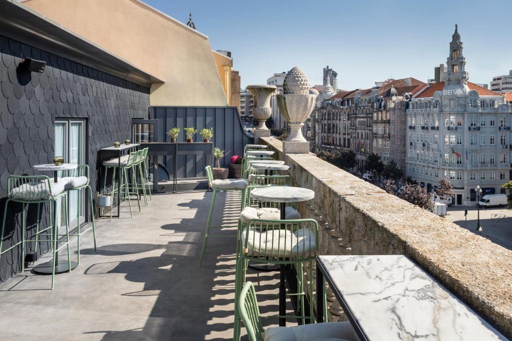 Terraço na cobertura com mesas de mármore, cadeiras verdes e vista sobre a cidade, no One Shot Aliados Goldsmith 12.