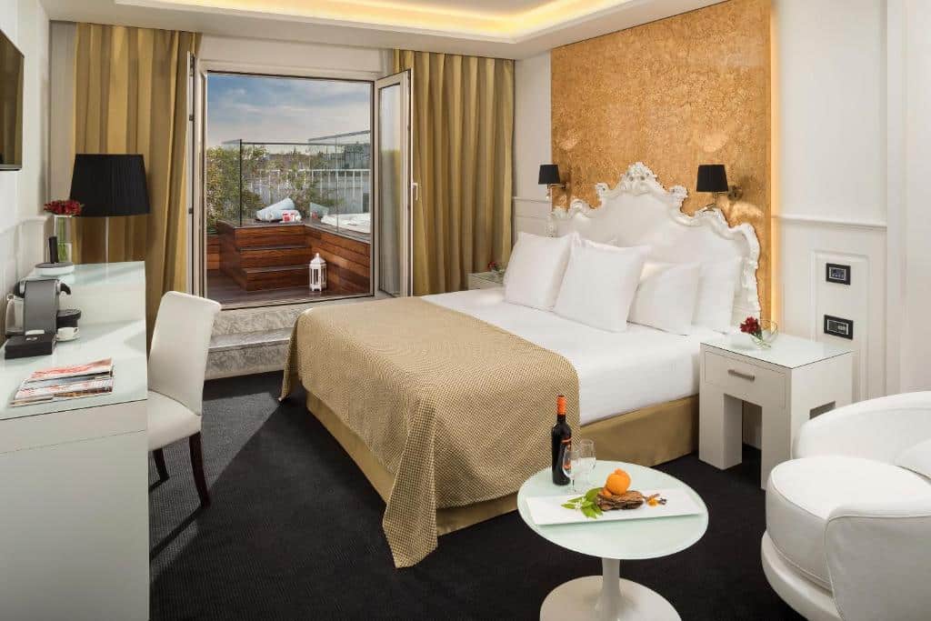 Quarto do Hotel Colón Gran Meliá com zona de estar, cama de casal, secretária e uma varanda com jacuzzi ao fundo.