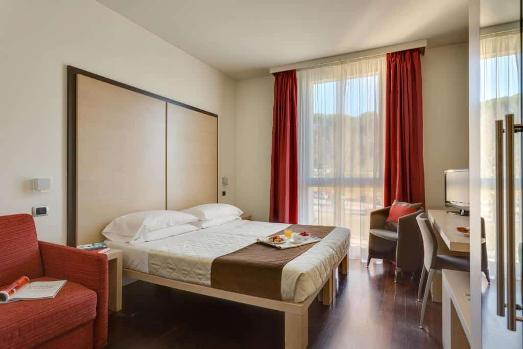 Quarto de hotel moderno com cama de casal, secretária e poltrona vermelha