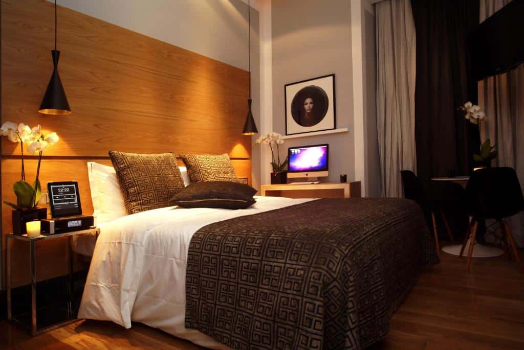 Quarto moderno no Browns Downtown Hotel com cama de casal, roupa de cama escura, candeeiros suspensos, uma pequena secretária e um retrato emoldurado na parede.