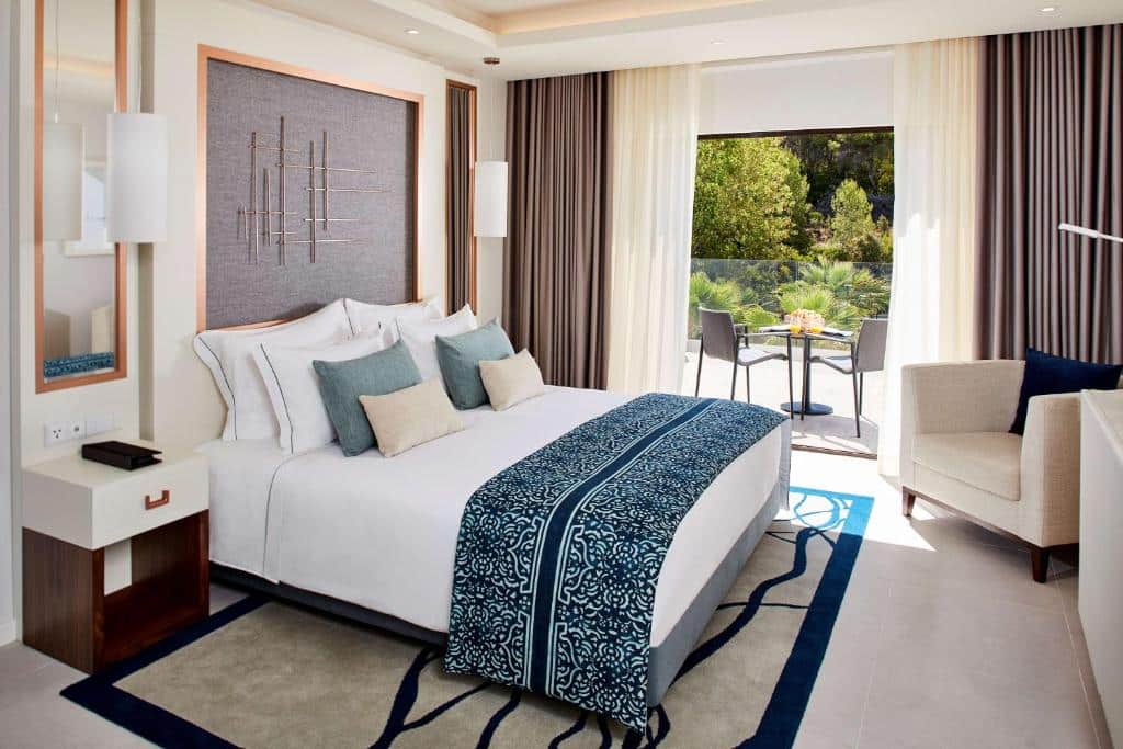 Quarto do Tivoli Carvoeiro, com cama de casal, cómoda e cadeirão.