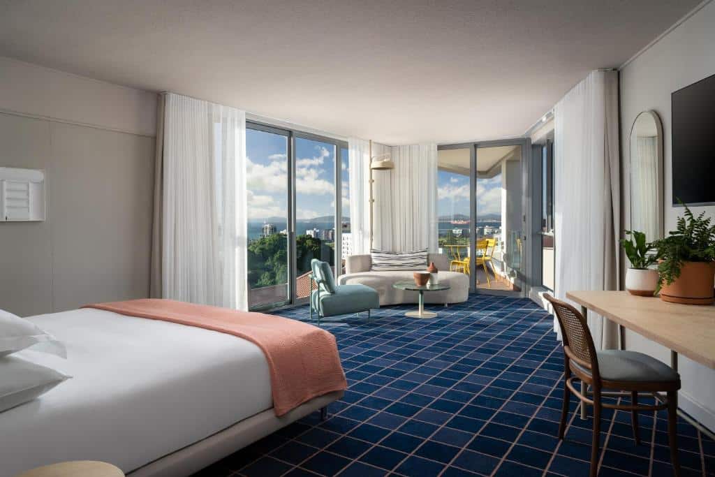 Quarto do Home Suite Hotels Sea Point com cama de casal, secretária, zona de estar, janelas grandes e varanda com vista panorâmica.