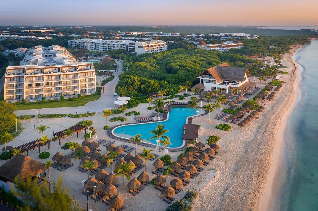 Ocean Riviera Paradise com tudo incluído de frente para o mar. Na areia, a estrutura do hotel conta com piscina, chapéus de sol de palha, espreguiçadeiras e o próprio hotel.