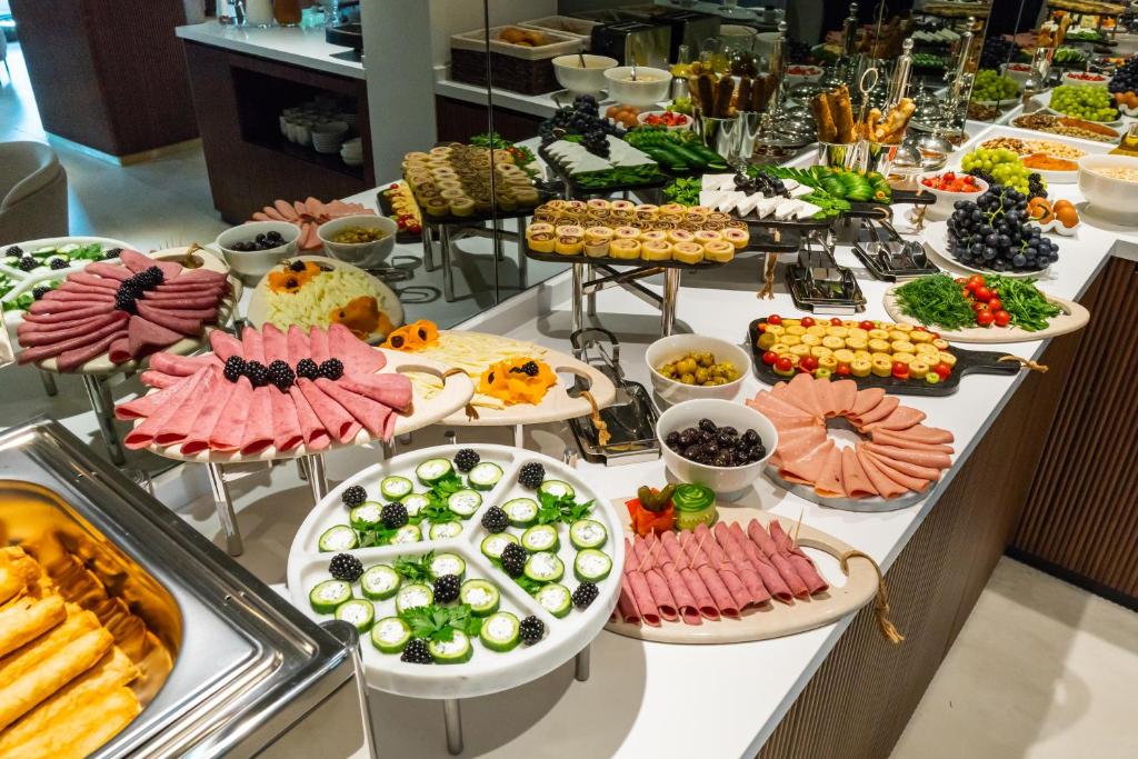 Uma mesa de bufete do Meg Hotel com enchidos variados, queijos, fruta, legumes, doces e tigelas de azeitonas e outros acompanhamentos.