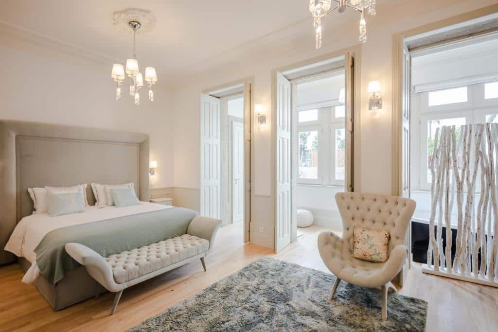 Quarto do Porto Deluxe Apartments, com cama de casal à esquerda, um sofá aos pés da cama e uma poltrona em frente.