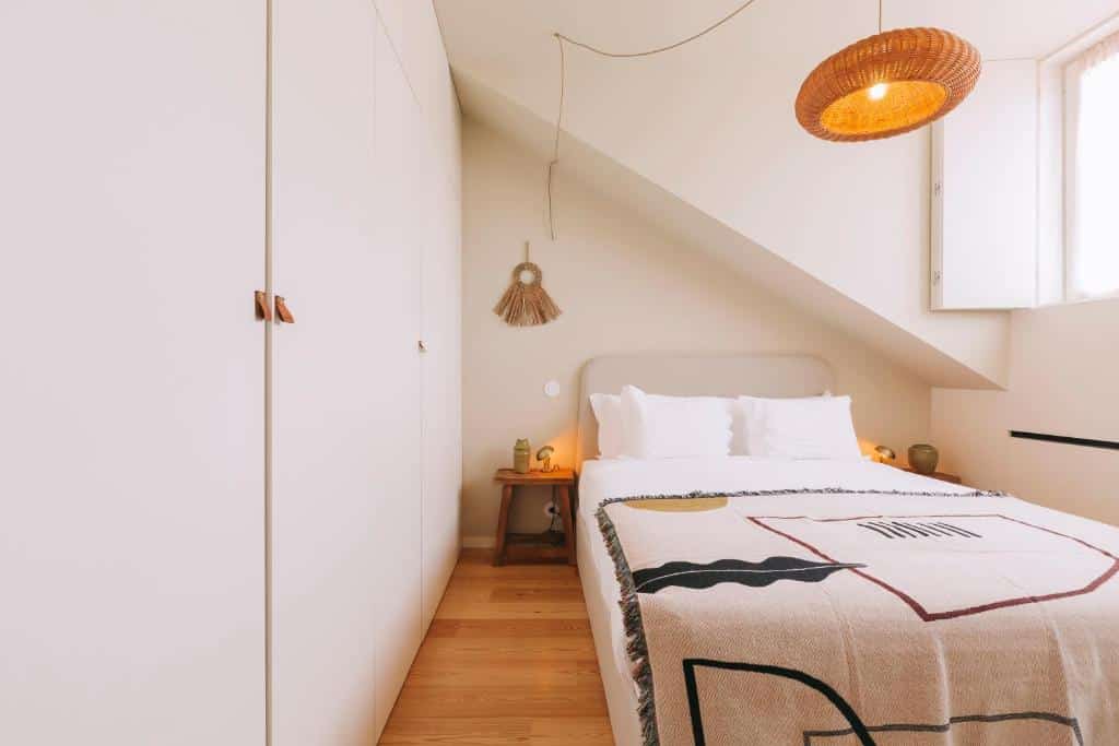 Quarto do Village Aparthotel By BOA, com cama de casal à direita e duas mesas de cabeceira.