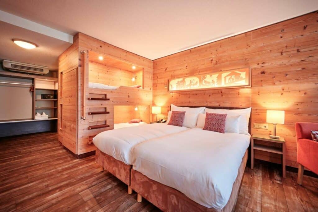 Quarto do Hotel Interlaken com cama de casal ao centro e beliche ao lado.