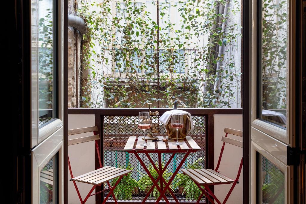 Pequeno-almoço numa varanda com vista para um jardim arborizado, duas taças de vinho rosé e uma garrafa numa mesa de madeira rústica, no Palazzo Residenza Madre by Dimorra.